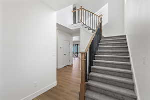 Staircase with wood finished floors and a towering ceiling