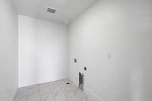 Washroom featuring hookup for a washing machine, light marble finish flooring, and electric dryer hookup