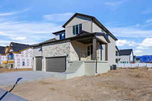 View of front facade with a garage, board and batten siding, stone siding, driveway, and a mountain view