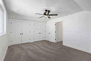 Unfurnished bedroom featuring two closets, carpet floors, a ceiling fan, and a textured ceiling