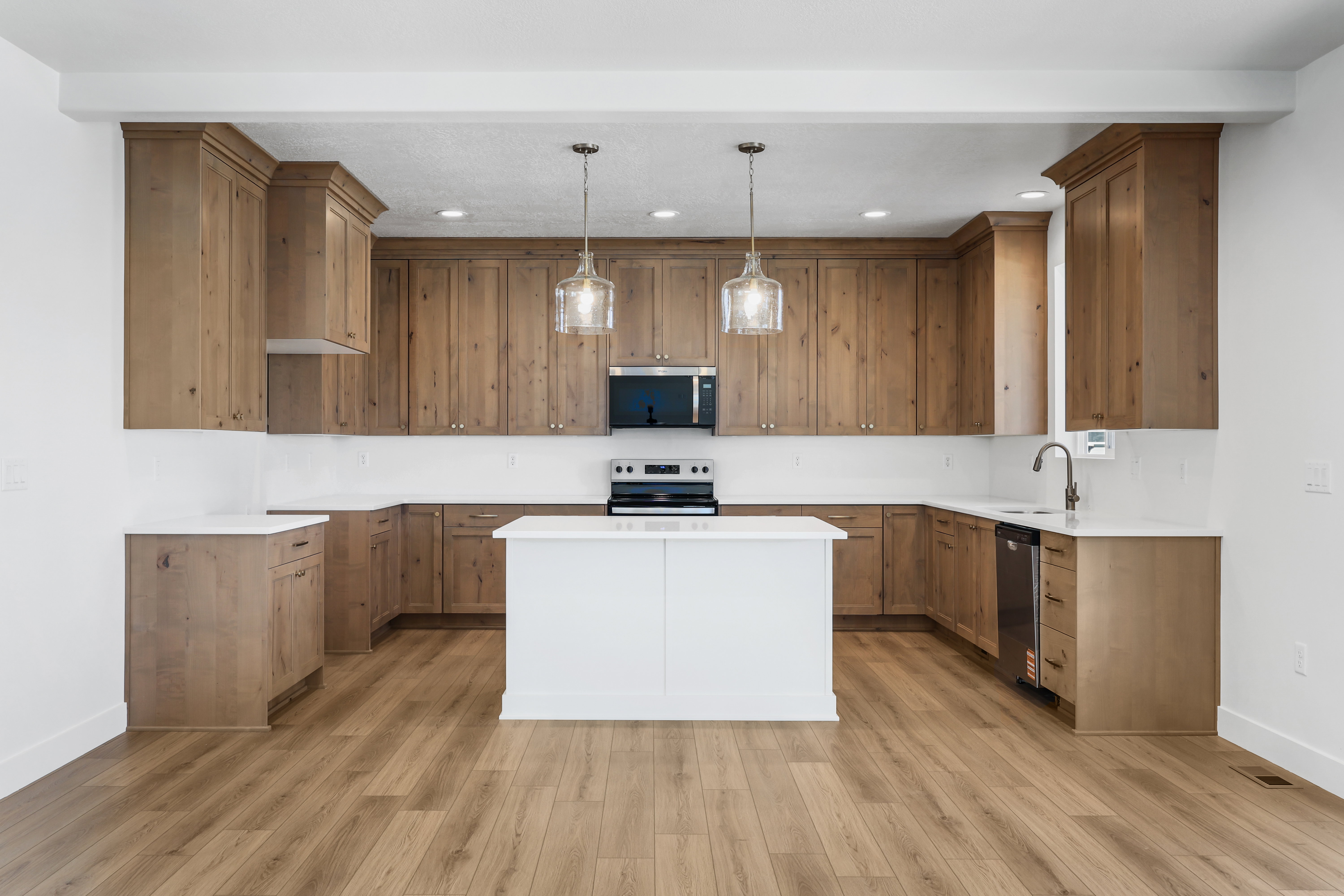 Kitchen featuring pendant lighting, a kitchen island, brown cabinets, stainless steel appliances, and light wood finished floors