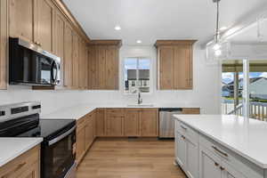 Kitchen with appliances with stainless steel finishes, healthy amount of natural light, pendant lighting, white cabinets, and recessed lighting