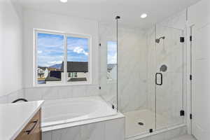 Bathroom featuring vanity, a garden tub, a marble finish shower, and recessed lighting
