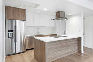 Kitchen with white cabinets, stainless steel appliances, modern cabinets, light wood-style floors, and brown cabinetry