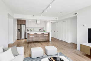 Living area featuring light wood-style floors and rail lighting