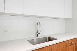 Kitchen with modern cabinets, white cabinets, and light stone countertops