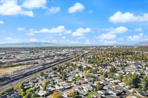 Aerial view of property and surrounding area featuring mountains and nearby suburban area
