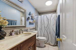 Full bath featuring curtained shower, vanity, light tile patterned floors, and tile walls