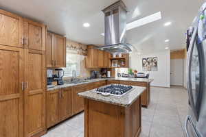 Kitchen featuring light stone countertops, a peninsula, appliances with stainless steel finishes, light tile patterned floors, and recessed lighting