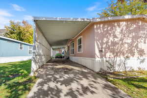 View of property exterior with concrete driveway, a lawn, and an attached carport
