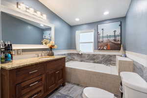 Bathroom with a garden tub, vanity, recessed lighting, light wood finished floors, and tile walls
