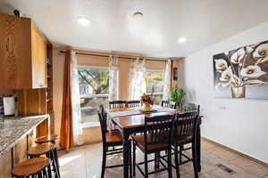Dining room with a textured ceiling, recessed lighting, and light tile patterned flooring