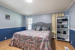 Bedroom with light wood-style floors and crown molding