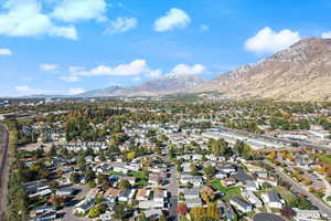 Aerial view of property and surrounding area with nearby suburban area and a mountain backdrop