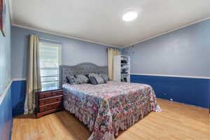 Bedroom with crown molding and wood finished floors