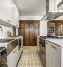 Kitchen featuring high end stove, white cabinets, island range hood, recessed lighting, and washer / clothes dryer