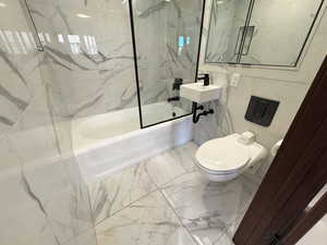 Full bathroom featuring marble finish floors, a combined bath / shower with marble tile walls and floors