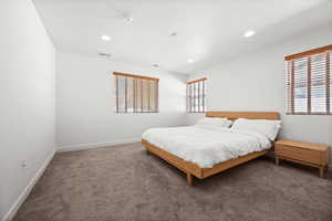 Carpeted bedroom with multiple windows and recessed lighting