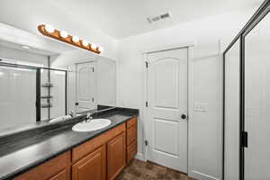 Bathroom featuring a shower stall, a textured ceiling, vanity, and stone finish flooring