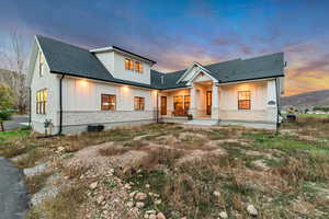 Modern farmhouse style home with board and batten siding, stone siding, roof with shingles, and a patio