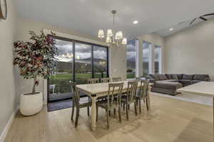 Dining space featuring a mountain view, light wood-style flooring, recessed lighting, vaulted ceiling, and a chandelier