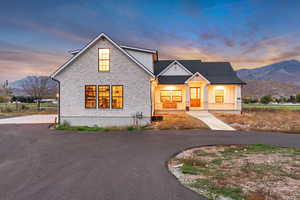 Modern inspired farmhouse featuring a mountain view, board and batten siding, stone siding, and covered porch