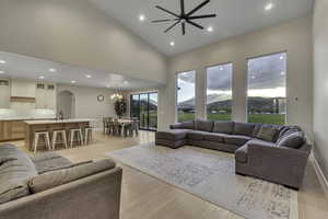 Living room with recessed lighting, high vaulted ceiling, a mountain view, arched walkways, and light wood-style floors