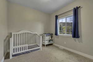 Carpeted bedroom featuring a nursery area and baseboards