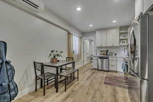 Kitchen with appliances with stainless steel finishes, light countertops, white cabinets, recessed lighting, and light wood-type flooring