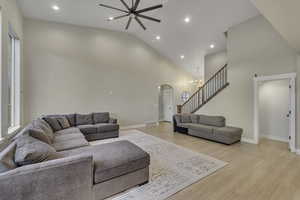 Living room with a chandelier, arched walkways, light wood finished floors, recessed lighting, and high vaulted ceiling