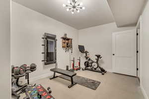 Exercise room featuring a chandelier, concrete flooring, and a textured ceiling