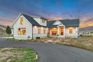 Modern farmhouse style home with stone siding, board and batten siding, covered porch, a mountain view, and a shingled roof