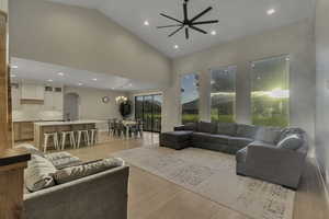 Living room featuring light wood-style floors, recessed lighting, arched walkways, high vaulted ceiling, and a ceiling fan
