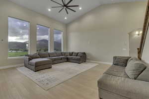 Living room featuring a mountain view, high vaulted ceiling, arched walkways, light wood finished floors, and recessed lighting