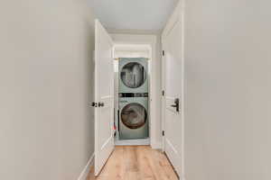 Laundry area with estacked washer and dryer and light wood-style floors