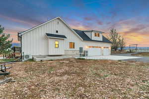 Modern farmhouse style home with board and batten siding, a shingled roof, concrete driveway, a garage, and stone siding