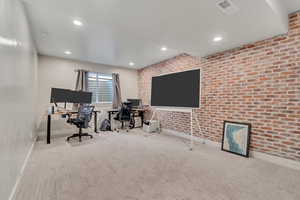 Carpeted office space with brick wall and recessed lighting
