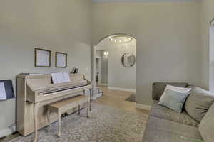 Living room featuring arched walkways, a high ceiling, and light wood finished floors
