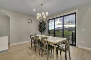 Dining area featuring a mountain view, light wood-style floors, arched walkways, and recessed lighting