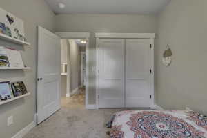 Bedroom with light colored carpet and a closet
