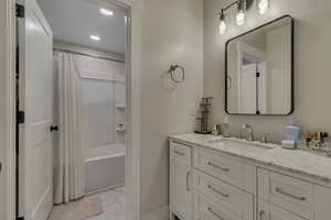 Full bathroom featuring vanity, shower / bath combo, light marble finish flooring, and recessed lighting