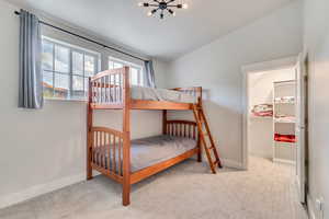 Bedroom featuring light colored carpet, lofted ceiling, and a chandelier