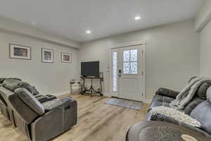 Living area with light wood-type flooring and recessed lighting