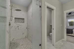 Bathroom with a marble finish shower, ensuite bath, marble look tiles, and ceiling fan