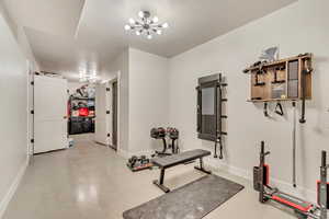Exercise room featuring concrete floors, a chandelier, and a textured ceiling