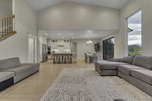 Living room with arched walkways, high vaulted ceiling, light wood-type flooring, a chandelier, and recessed lighting
