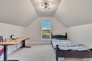 Bedroom with light carpet, a textured ceiling, and vaulted ceiling
