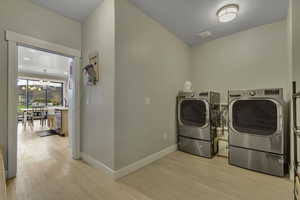 Laundry room with a chandelier, separate washer and dryer, and light wood finished floors