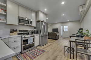 Kitchen featuring stainless steel appliances, open shelves, light wood-style floors, recessed lighting, and open floor plan