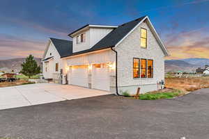 Modern farmhouse featuring a mountain view, stone siding, board and batten siding, a garage, and driveway